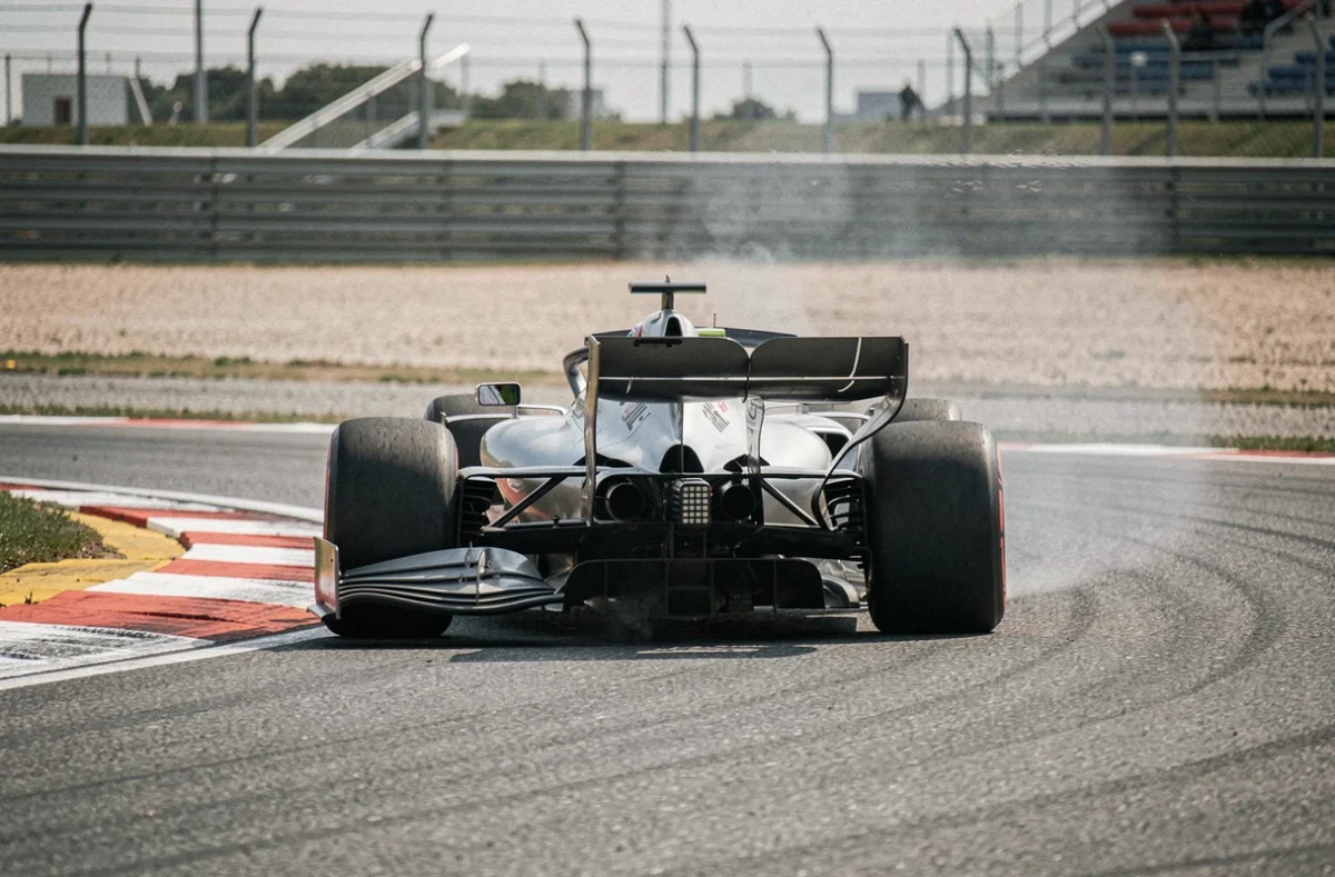 Monoplace F1 en pleine négociation de virage avec déformation visible des pneus arrière sur circuit